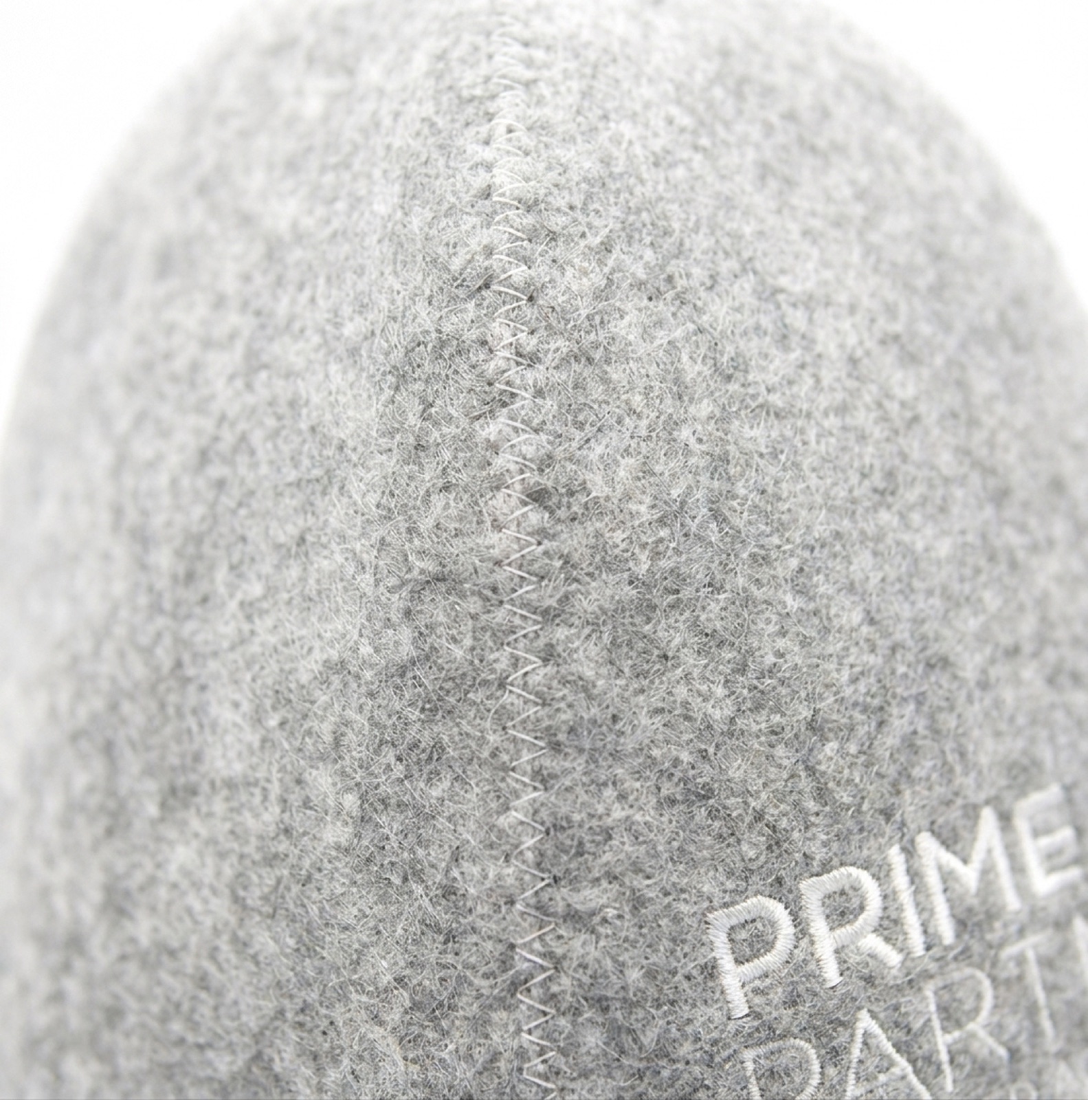 Macro detail of the grey wool felt surface and the white zigzag blanket stitch along a seam.